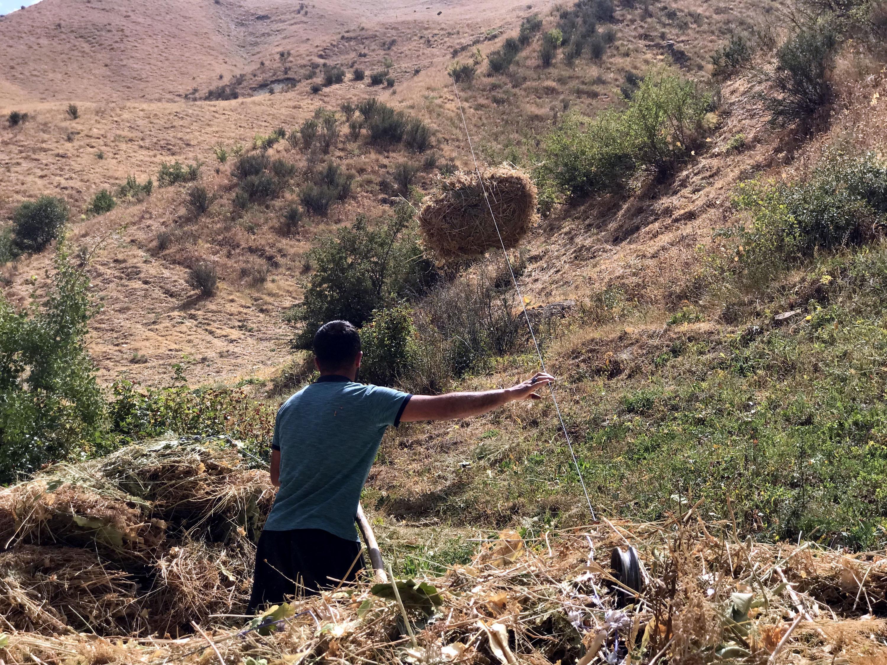 Villagers transport hay bales to the village by zipline