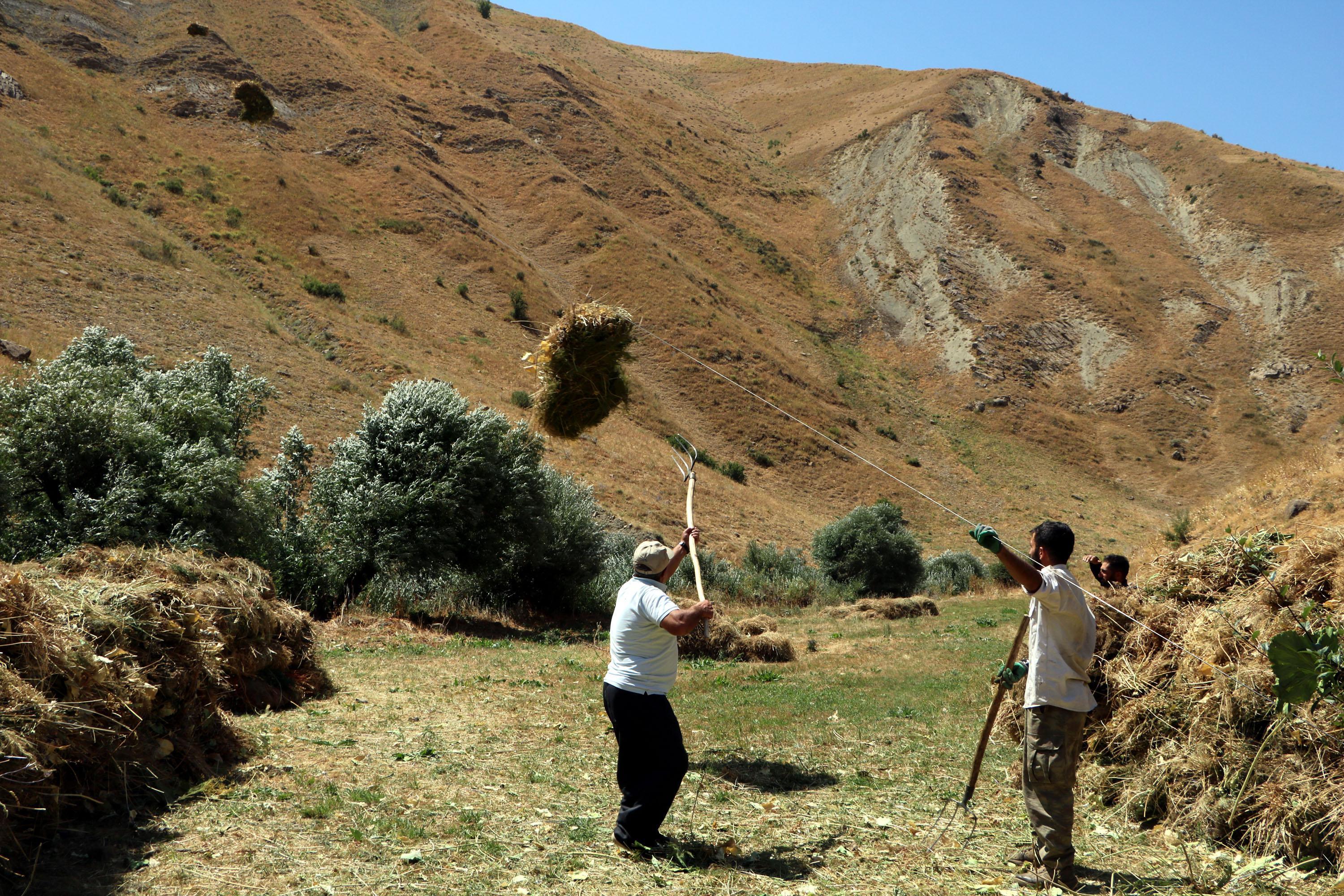 Villagers transport hay bales to the village by zipline