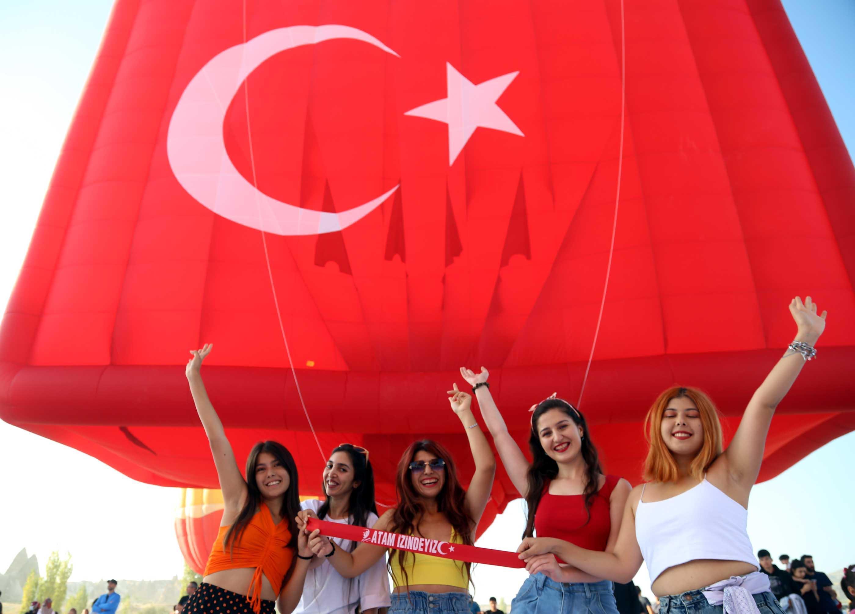 Hot air balloons take off with Ataturk poster and flag in Cappadocia