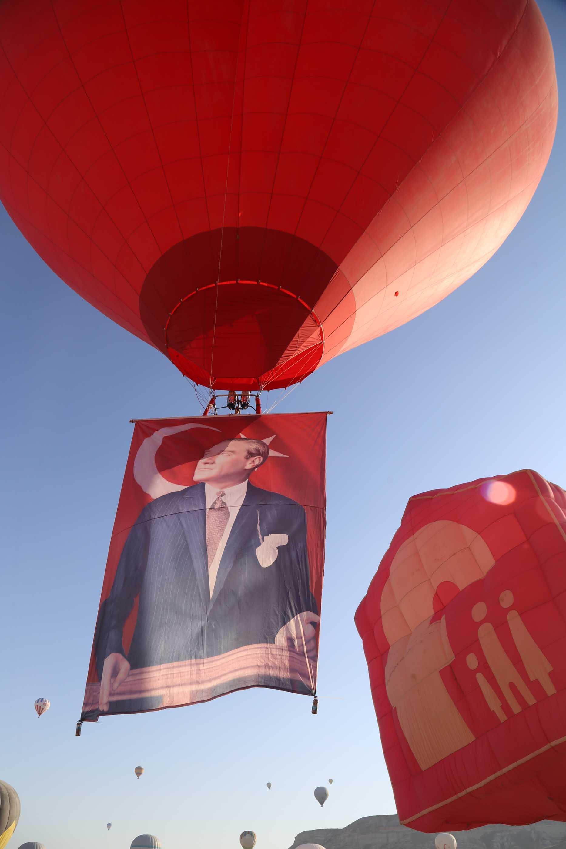 Hot air balloons take off with Ataturk poster and flag in Cappadocia