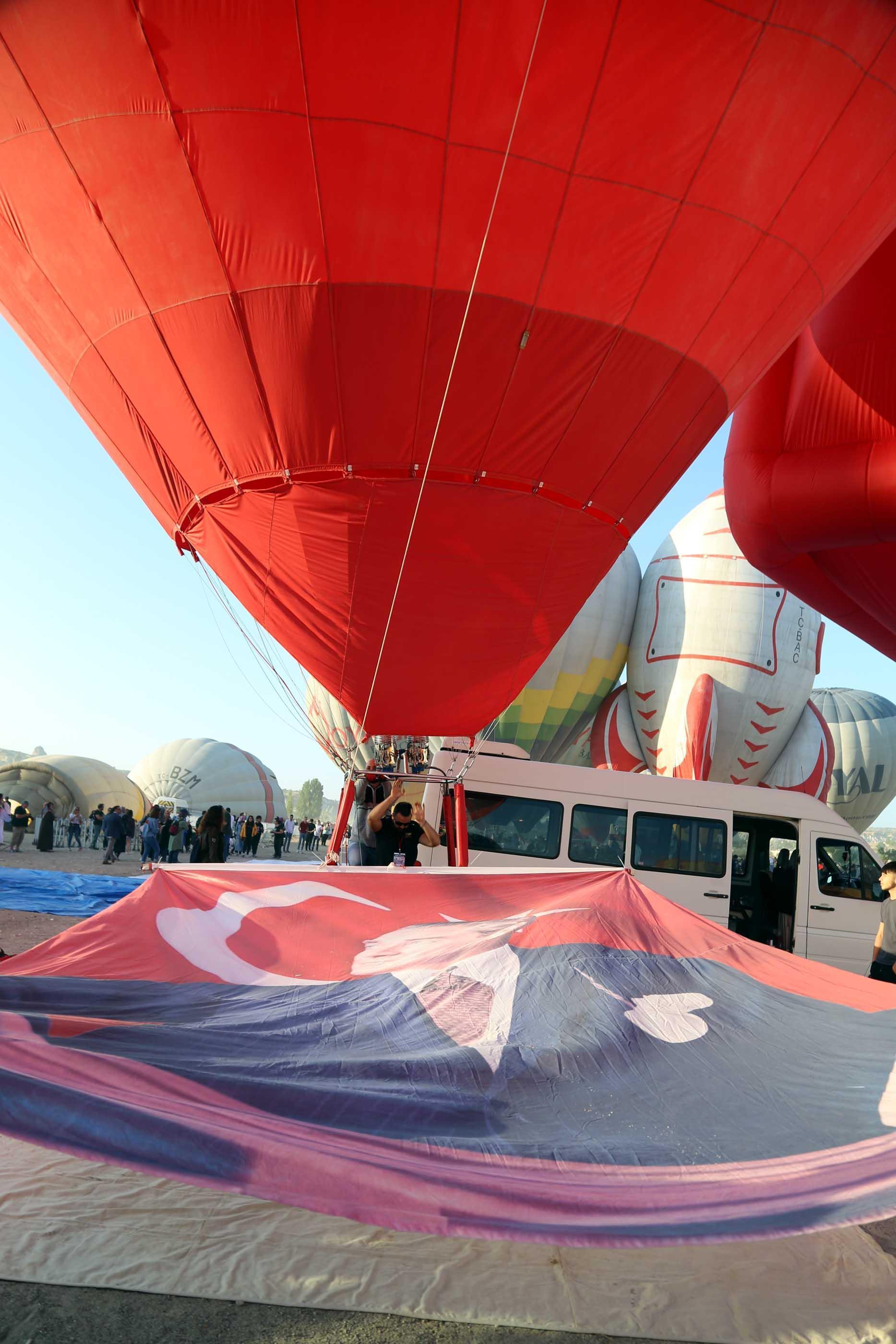 Hot air balloons take off with Ataturk poster and flag in Cappadocia