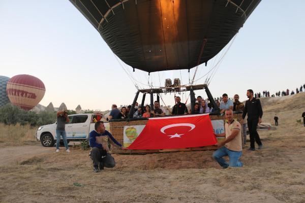 Hot air balloons take off with Ataturk poster and flag in Cappadocia