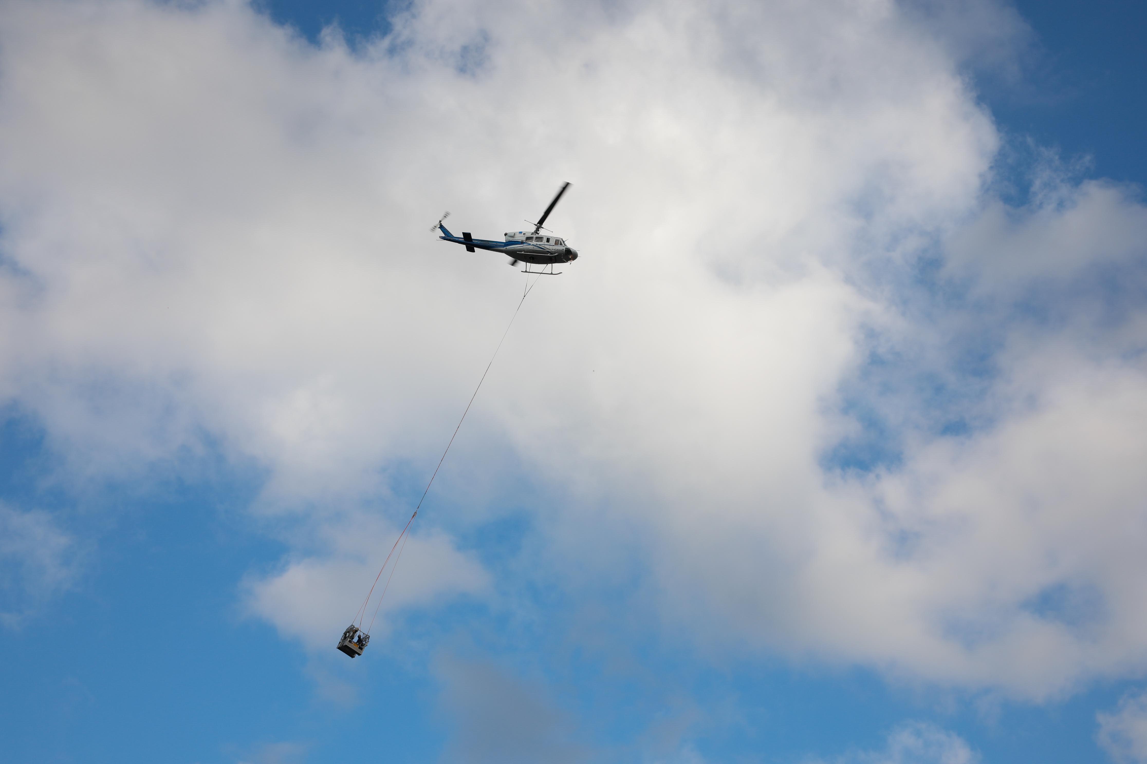 Helikoptere bağlı sepetle elektrik iletim hatlarına bakım yaparken ölüme meydan okuyorlar