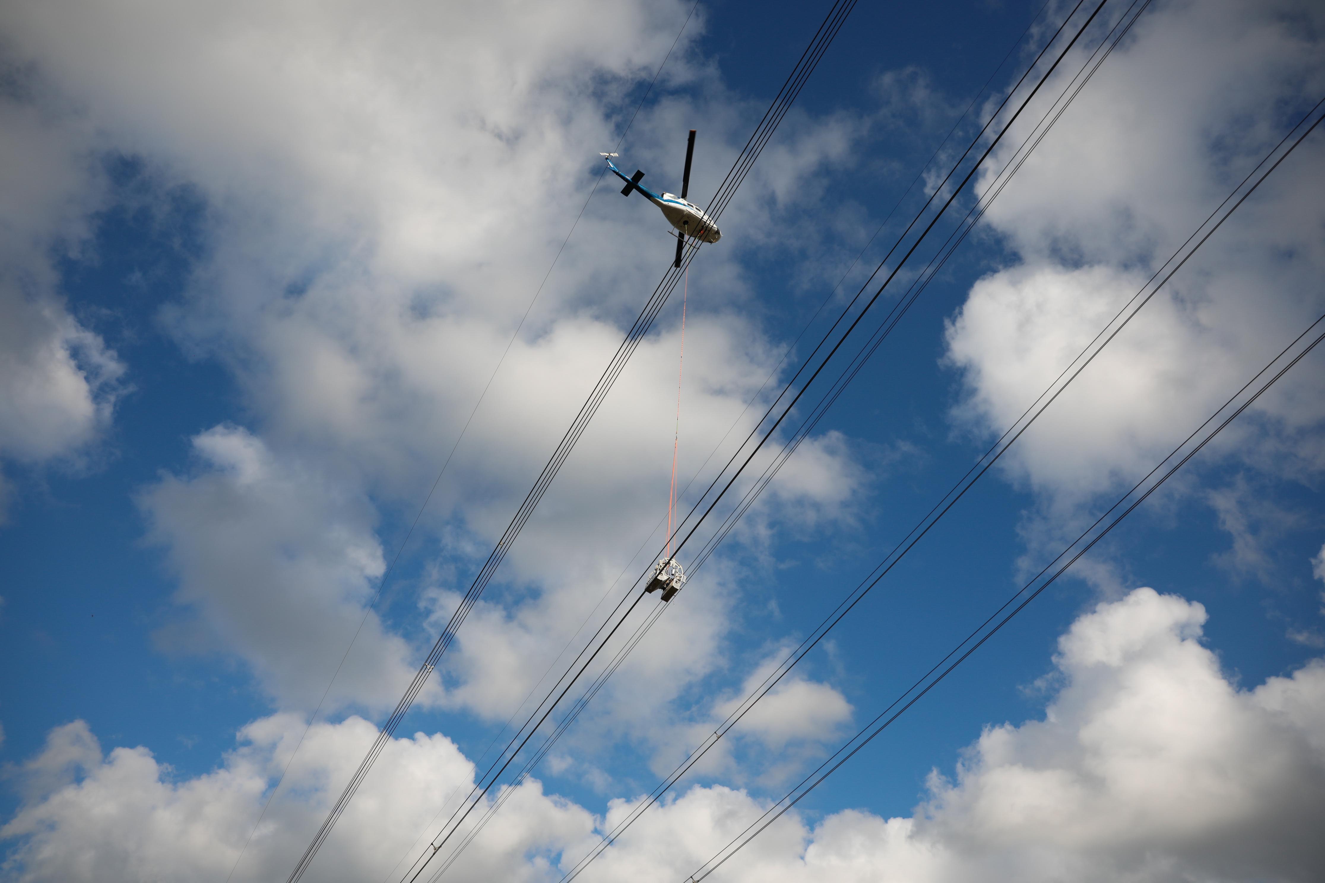 Helikoptere bağlı sepetle elektrik iletim hatlarına bakım yaparken ölüme meydan okuyorlar