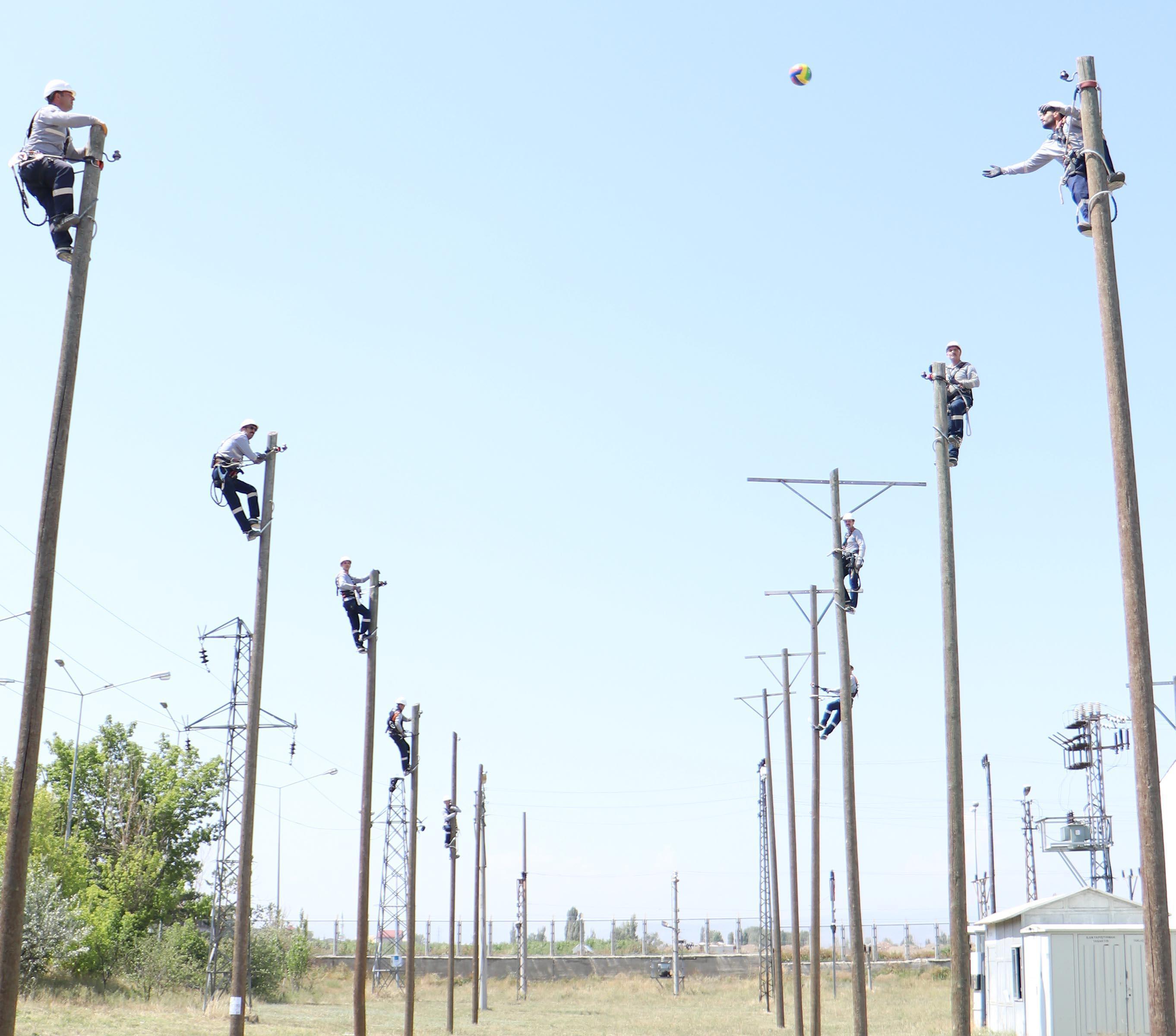 Electricians playing volleyball on top of poles for balance training