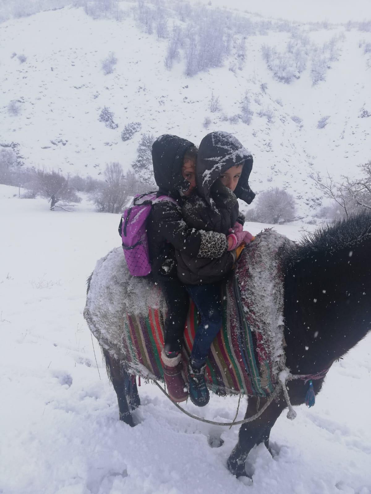 Kar yolu kapatınca, çocukları at sırtında okula götürdü