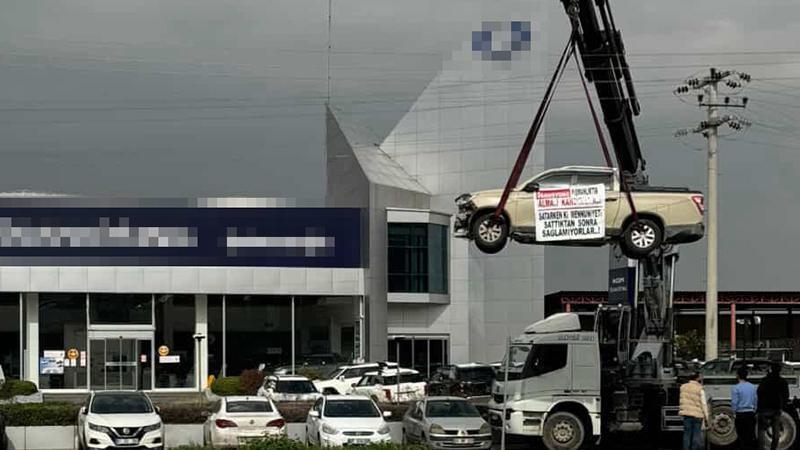 Aldığı sıfır kamyoneti, hatalı çıktığını öne sürüp, bayinin önünde vinçle kaldırarak sergiledi