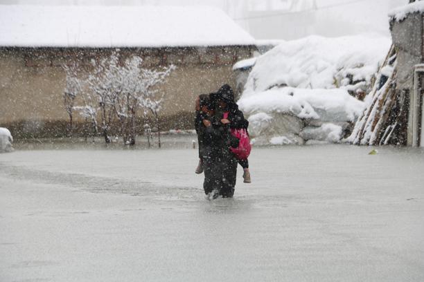 Evinin önünde biriken su nedeniyle çocuklarını sırtında taşıyor