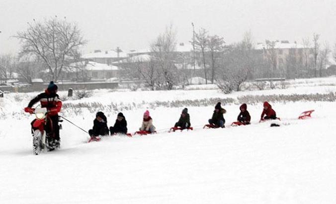 Motosiklete bağladığı kızaklarla çocukları karda eğlendirdi