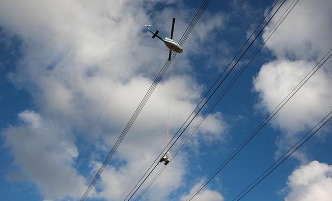 Helikoptere bağlı sepetle elektrik iletim hatlarına bakım yaparken ölüme meydan okuyorlar
