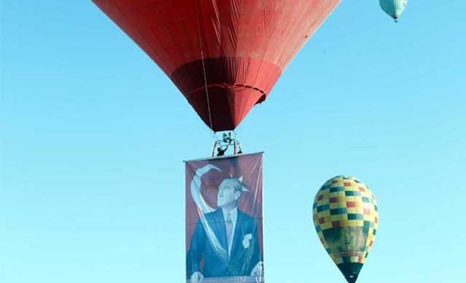 Hot air balloons take off with Ataturk poster and flag in Cappadocia