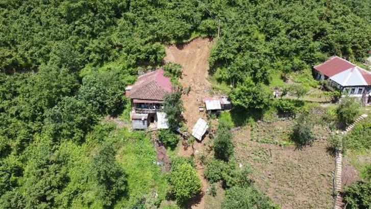Anne ve oğlu, heyelanda hasar gören evlerinin penceresinden çıkmış
