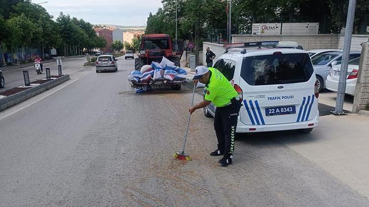 Polis, traktörden düşerek yola saçılan kuzu yemlerini topladı