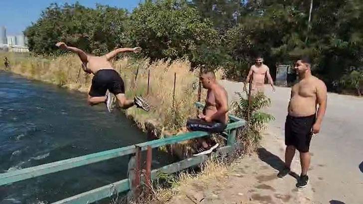 Tehlikeye aldırmadan sulama kanalında serinlediler