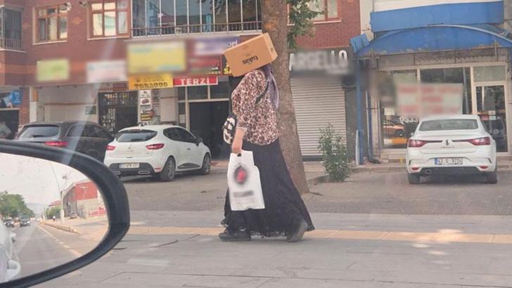 Başına karton kutu geçirerek sıcaktan korunmaya çalıştı