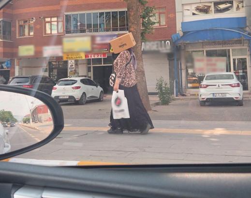 Başına karton kutu geçirerek sıcaktan korunmaya çalıştı