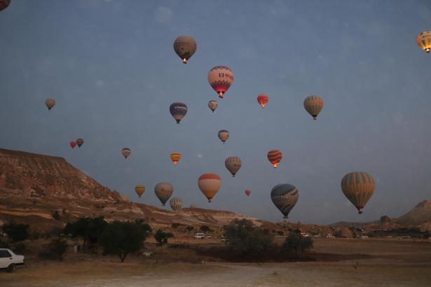 Kapadokya’ya tatil için gelen turistler, bölgeyi sıcak hava balonuyla izliyor