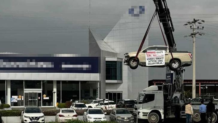 Aldığı sıfır kamyoneti, hatalı çıktığını öne sürüp, bayinin önünde vinçle kaldırarak sergiledi