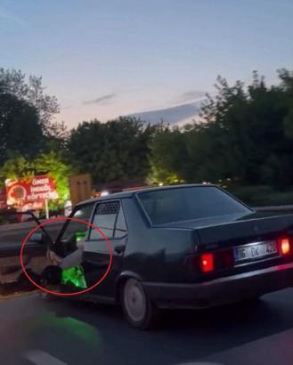 Otomobilinin sol ön kapısını açıp, ayağıyla tutarak trafikte ilerledi
