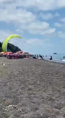 Sahilde motorlu yamaç paraşütüyle havalanırken tatilcilerin arasına daldı