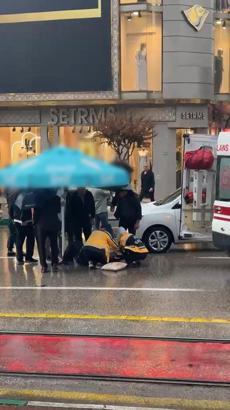 Otomobilin çarptığı yaralıyı yağmurdan korumak için şemsiye tuttular