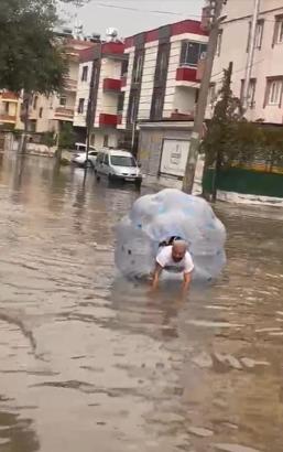 Sağanakta suyla dolan caddede içine girdiği büyük şeffaf balonla ilerledi
