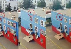 Okul çatısından pencerelere tutunarak inen çocuk kamerada