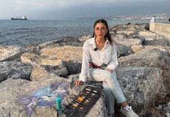 Depremzede ressam, sahildeki kayaları renklendiriyor