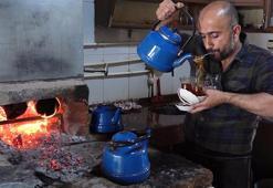Çay taleplerine yetişmek için ağzında süzgeçle bardakları dolduruyor