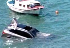 Denize uçan otomobilinin üzerinde oturup yardım bekledi
