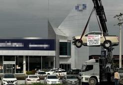 Aldığı sıfır kamyoneti, hatalı çıktığını öne sürüp, bayinin önünde vinçle kaldırarak sergiledi