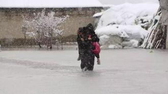 Evinin önünde biriken su nedeniyle çocuklarını sırtında taşıyor