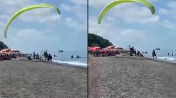Sahilde motorlu yamaç paraşütüyle havalanırken tatilcilerin arasına daldı