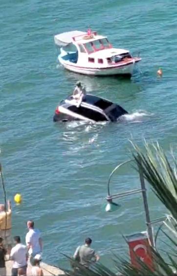 Denize uçan otomobilinin üzerinde oturup yardım bekledi
