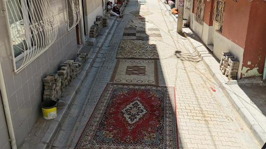 Mahalleli tozdan korunmak için onarılmayan yollara halı serdi