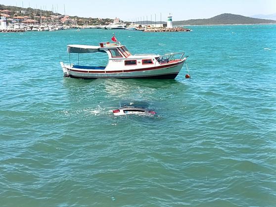 Denize uçan otomobilinin üzerinde oturup yardım bekledi