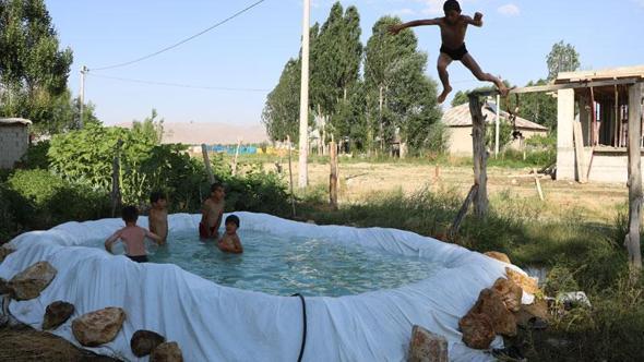 Sıcaktan bunalan çocuklar, brandayla oluşturulan havuzda serinliyor