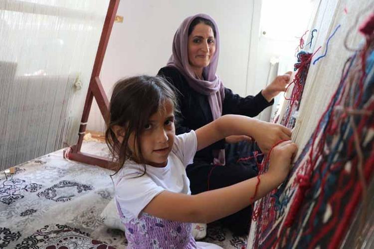 KIZINA KİLİM DOKUMACILIĞI ÖĞRETİYOR