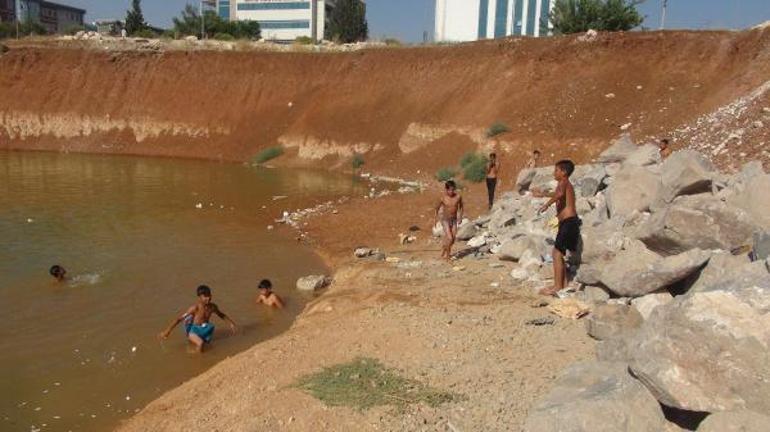 Çocuklar, inşaat temelini dolduran kirli suda yüzüyor