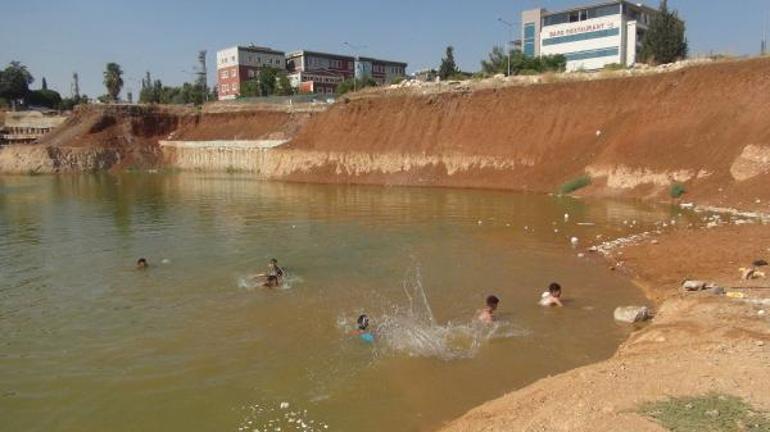Çocuklar, inşaat temelini dolduran kirli suda yüzüyor